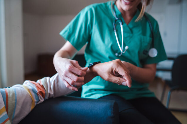 Smartwatch for health care. A woman from the medical health system wears a smartwatch for remote monitoring of vital signs on an elderly person - assisted living concept